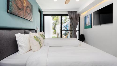 a bedroom with a white bed and a television at AP Natai Luxury Beachfront Pool Villas in Phang-nga