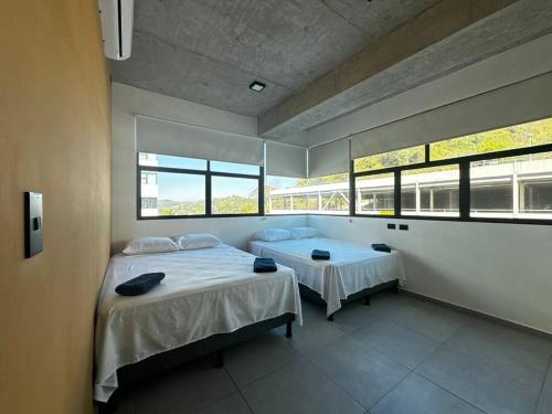 a bedroom with two beds and two windows at Spacious & Classy apartment in Santa Elena in Antiguo Cuscatlán