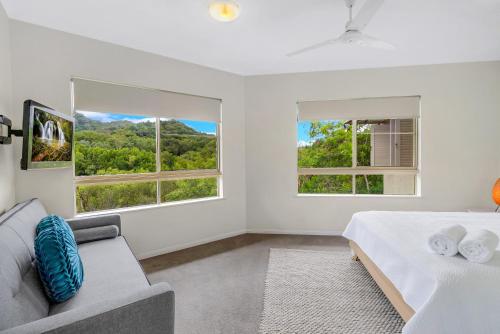 1 dormitorio blanco con 2 ventanas y sofá en Vacanze A Casa - Resort Just Minutes From The CBD, en Cairns North