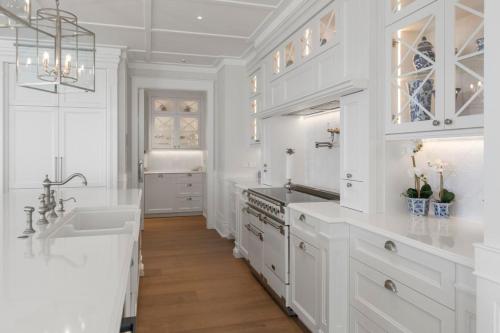 a white kitchen with a sink and a stove at Hampton on View Luxury Clifftop in Campbells Bay in Auckland