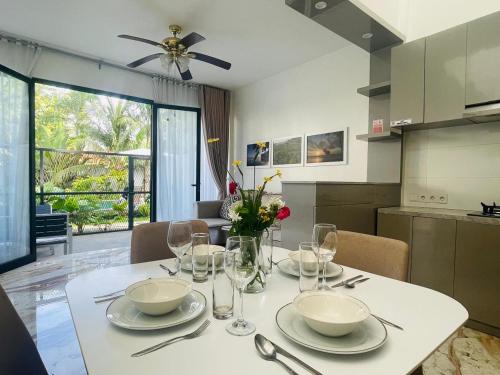 a table with plates and glasses on it in a kitchen at De Residence Pangandaran by Mabano Estates in Pangandaran