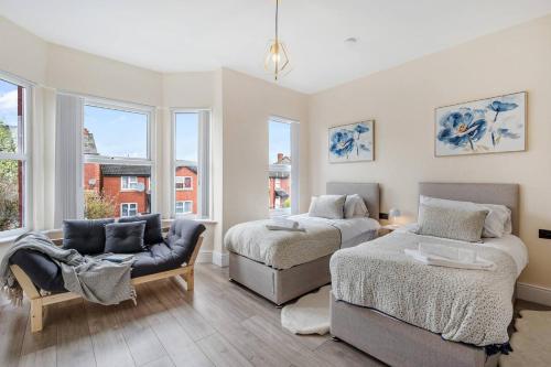1 dormitorio con 2 camas, sofá y ventanas en Pass the Keys Spacious Stylish House, en Mánchester