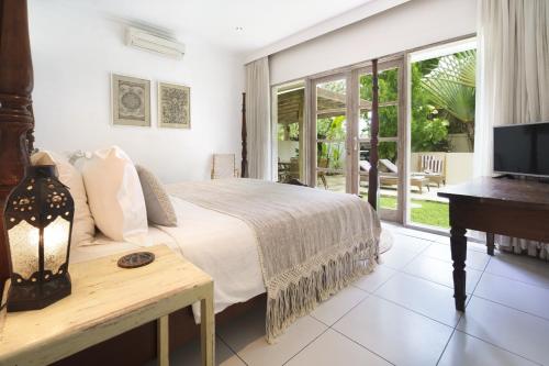 een slaapkamer met een bed en een televisie en een piano bij Villa Puri Pura in Canggu