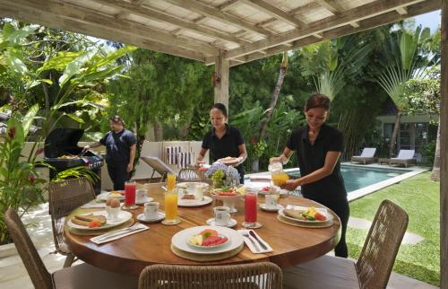 een groep mensen die rond een tafel zitten en eten bij Villa Puri Pura in Canggu