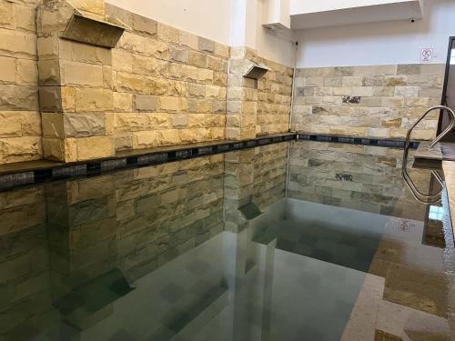 una piscina en una habitación con una pared de piedra en Rayana Resort Mitra Reddoorz, en Songgoriti
