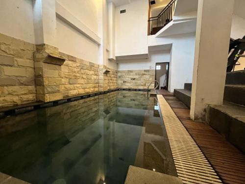 una piscina en un edificio con una pared de piedra en Rayana Resort Mitra Reddoorz, en Songgoriti