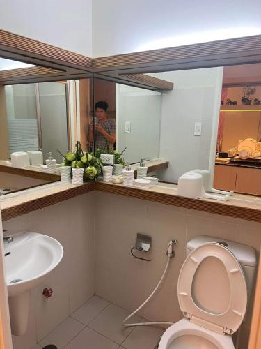 un homme prenant une photo d'une salle de bains avec toilettes et lavabo dans l'établissement SMDC FORT TAGAYTAY STAYCATION, à Kaybagal