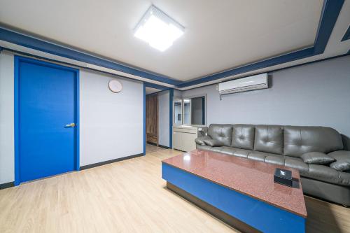 a living room with a leather couch and a blue door at Noblesse Hotel in Jeju