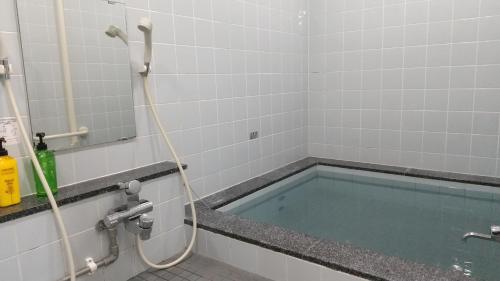 a bath tub with a hose in a bathroom at ビジネスホテルパークイン石巻 in Inai
