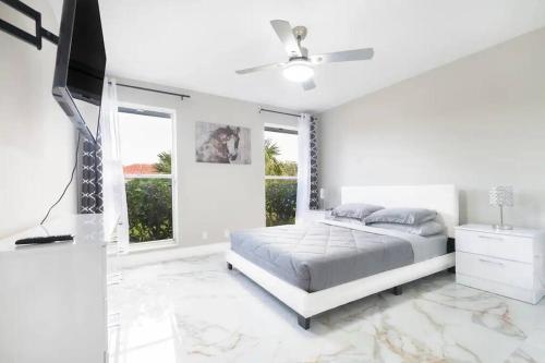 a white bedroom with a bed and a ceiling fan at Modern Lakefront Home in Wellington