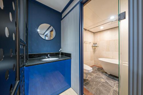 a bathroom with blue walls and a sink and a tub at Noblesse Hotel in Jeju