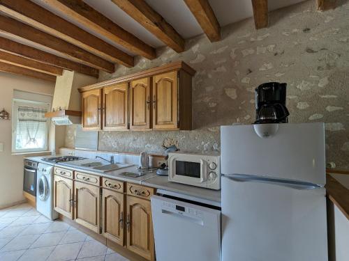La cuisine est équipée d'un réfrigérateur blanc et d'un four micro-ondes. dans l'établissement Ancienne ferme avec jardin, trampoline et pétanque entre Valençay et Beauval - FR-1-591-217, à Frédillé