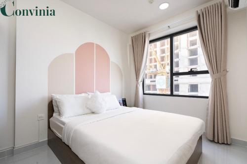 a white bedroom with a large bed and a window at Soho Apartment By Convinia in Ho Chi Minh City
