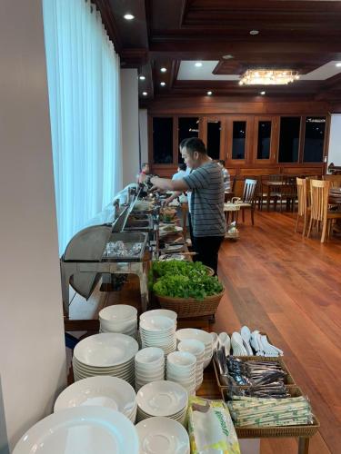 um homem de pé numa mesa com pratos e tigelas em HotelLaoMixay em Savannakhet
