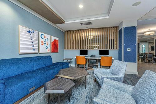 a living room with a blue couch and chairs at Holiday Inn Express & Suites Charleston Arpt-Conv Ctr Area by IHG in Charleston