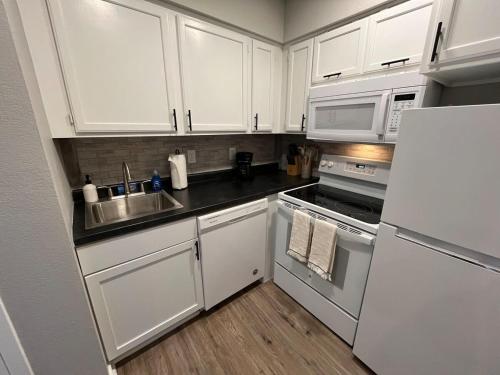 a kitchen with white cabinets and a sink and a refrigerator at Aksarben 1 Bedroom-Close to I-80 in Omaha
