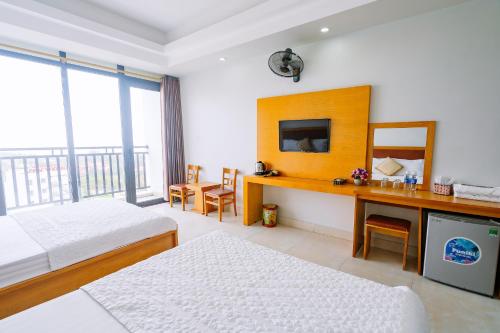 a bedroom with two beds and a desk with a mirror at UFJ HOTEL Sầm Sơn in Sầm Sơn