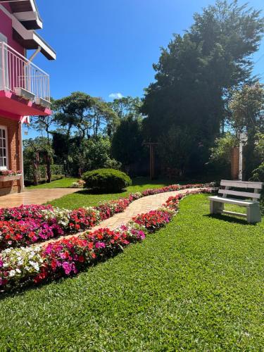 um banco de parque sentado ao lado de uma cama de flores em Pousada Pink Village em Campos do Jordão