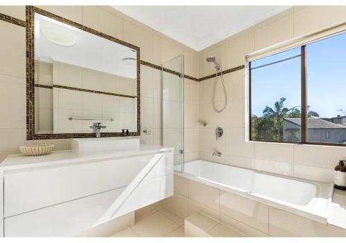 a bathroom with a tub and a sink and a window at Noosa Riverside Getaway in Noosa Heads