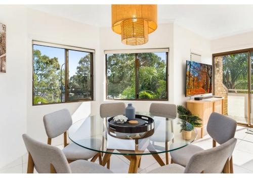 a dining room with a glass table and chairs at Noosa Riverside Getaway in Noosa Heads