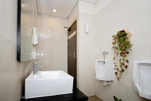 ein Badezimmer mit einem Waschbecken, einem Urinal und einem WC in der Unterkunft Zodiak Asia Afrika by KAGUM Hotels in Bandung