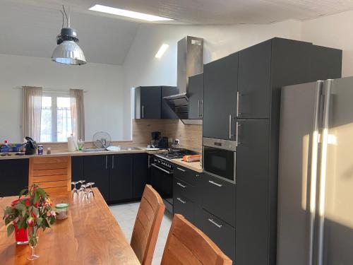 une cuisine avec une table en bois et un réfrigérateur dans l'établissement Maison Traditionnelle Rénovée, Proche Plage, Barbâtre - Terrasse, Wifi, Confort Modern - FR-1-426-371, à Barbâtre