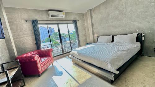 a bedroom with a bed and a red chair at Norn Nee Nor in Chiang Mai