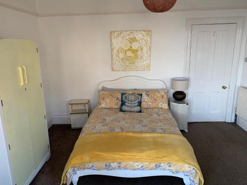 a bedroom with a bed with a yellow bedspread at Spectacular sea view double, with exclusive bathroom & use of patio and bike store in Margate