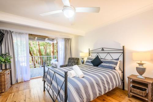 a bedroom with a large bed and a balcony at Treetops in Pearl Beach