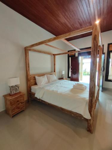 a bedroom with a large bed with a wooden frame at Molog guest house in Ubud