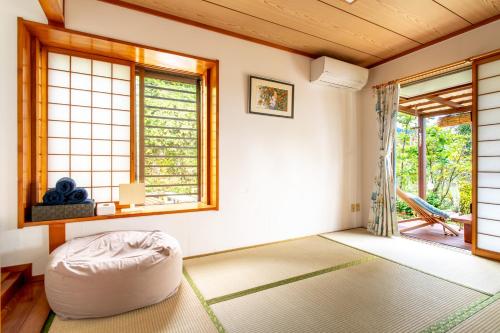 a living room with a ottoman in a room with windows at Beach House Yomitan in Yomitan