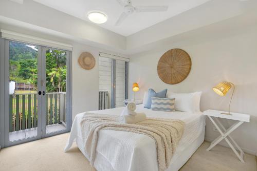 een witte slaapkamer met een bed en een balkon bij Botanical- Edge Hill Village in Edge Hill