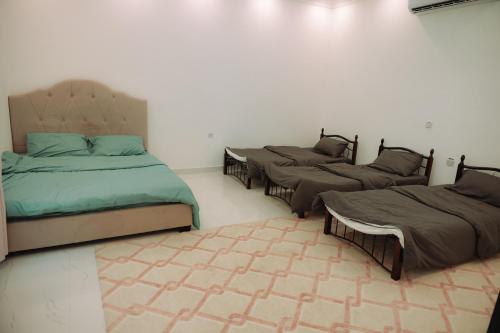 three beds are lined up in a room at Al Fay Farmhouse in Sinādil