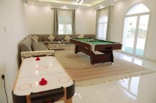 a living room with a pool table and a couch at Al Fay Farmhouse in Sinādil