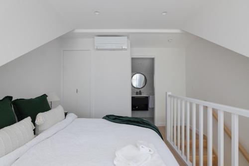 a white bedroom with a bed and a staircase at Unionelle a Luxe Newtown Terrance in Sydney