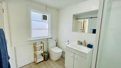 Baño blanco con aseo y lavamanos en Little Home on Glanmire, en Wellington