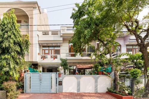 a building with a fence and trees in front of it at Stylish & Cozy Retreat with Jacuzzi in Jaipur
