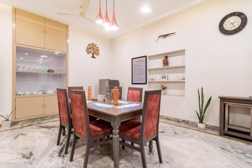 a dining room with a table and chairs and a clock at Stylish & Cozy Retreat with Jacuzzi in Jaipur