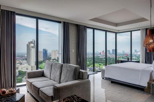 1 dormitorio con cama, sofá y ventana grande en Whiz Luxe Hotel Spazio Surabaya en Surabaya