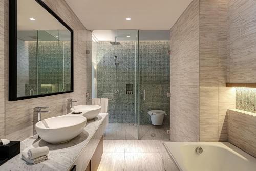 a bathroom with a tub and a sink and a shower at Whiz Luxe Hotel Spazio Surabaya in Surabaya