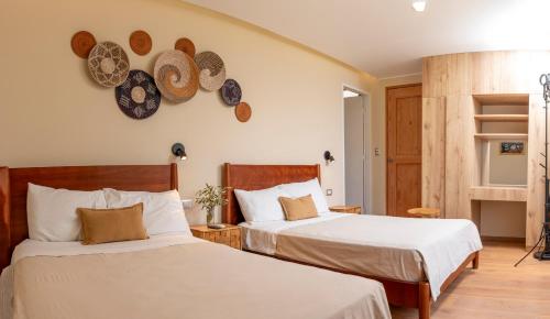 dwa łóżka w pokoju z kapeluszami na ścianie w obiekcie Acari Hotel Resort 