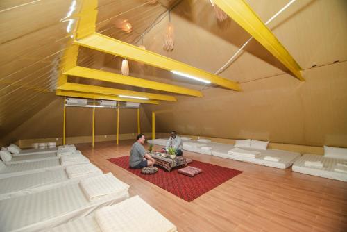 two people sitting on a red rug in a large room at Wind's House Ha Giang in Ha Giang
