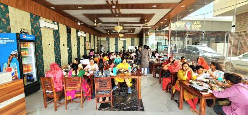 un grupo de personas sentadas en mesas en un restaurante en SHREE KESHAV RESTRO AND ROOMS, en Khātu