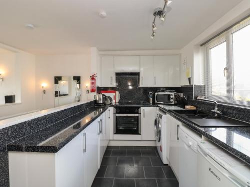 a kitchen with white cabinets and black counter tops at The Heights in Bowness-on-Windermere