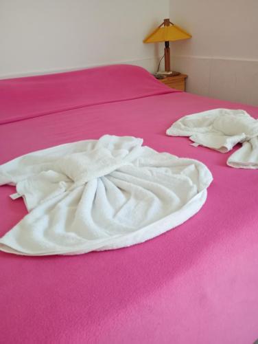 dos mantas blancas sobre una cama rosa en Posada la Península en Gualeguaychú