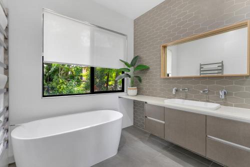 a bathroom with a tub and a sink and a window at Ohana - The Ultimate Family Pool Escape in Kewarra Beach