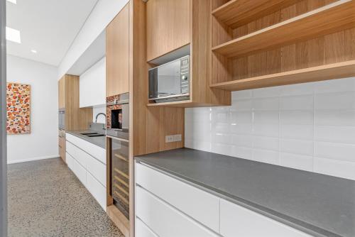 a kitchen with white counters and wooden cabinets at Ohana - The Ultimate Family Pool Escape in Kewarra Beach