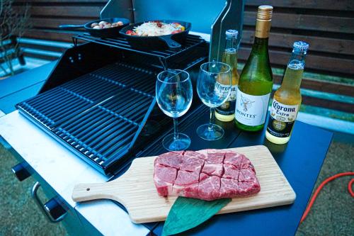 a piece of meat on a cutting board next to wine glasses at TAITO BEACH HOUSE in Ichigaya