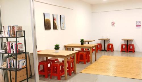 a row of tables and red chairs in a room at Sunset Homestay - Backpacker Hostel Self Checkin in Kuching