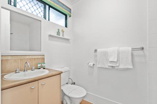 a bathroom with a sink and a toilet and a window at Sunset Oasis in Airlie Beach